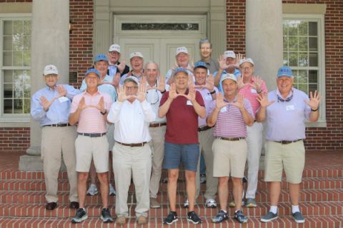 group of older men holding up hands
