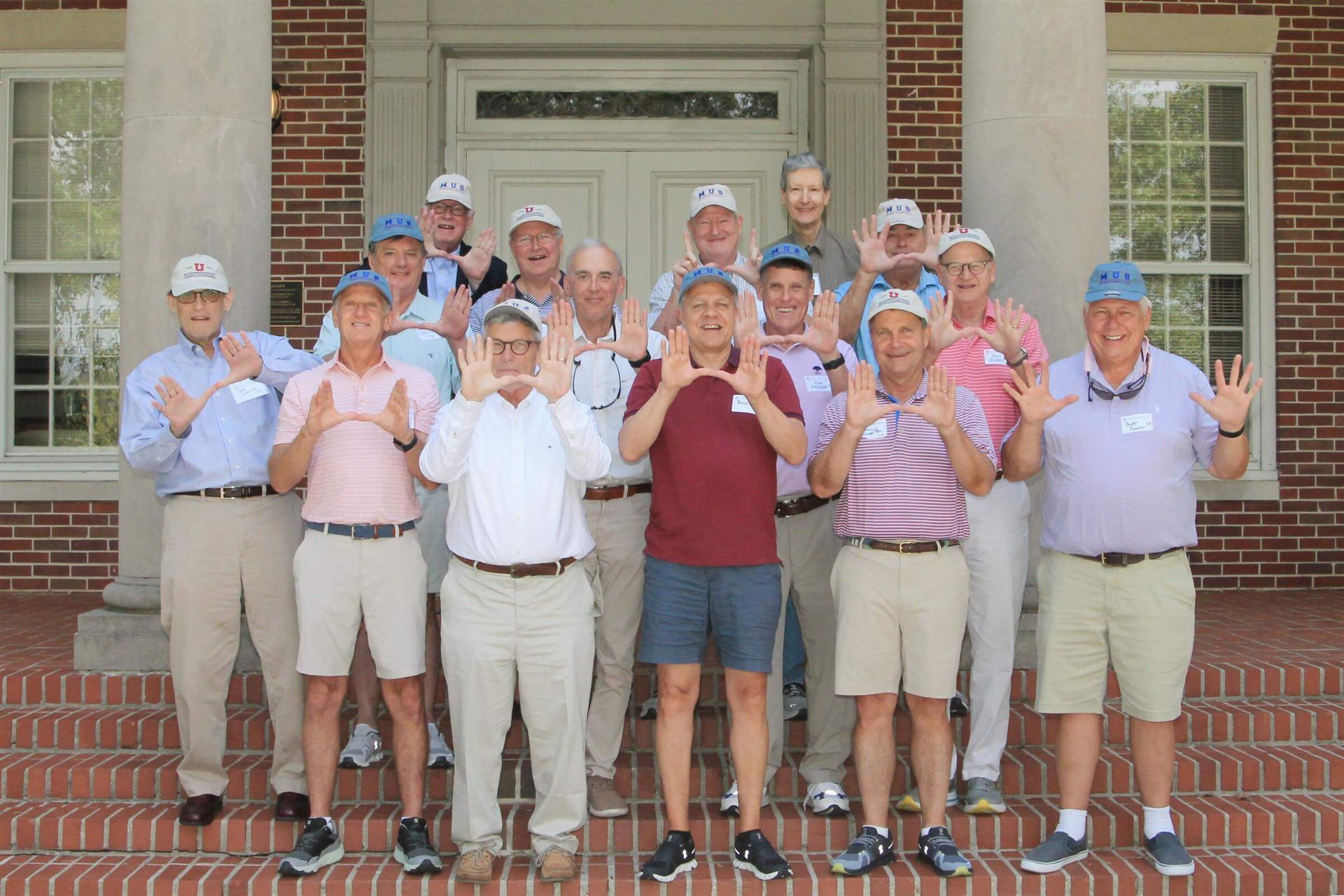 group of older men holding up hands