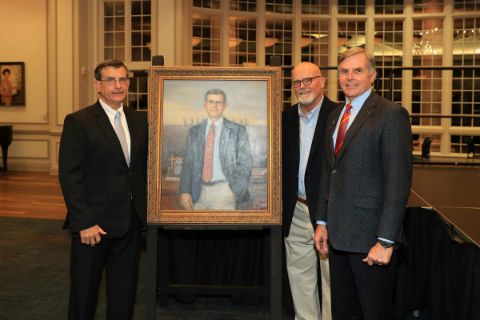 Men posing with portrait painting of Eddie Batey