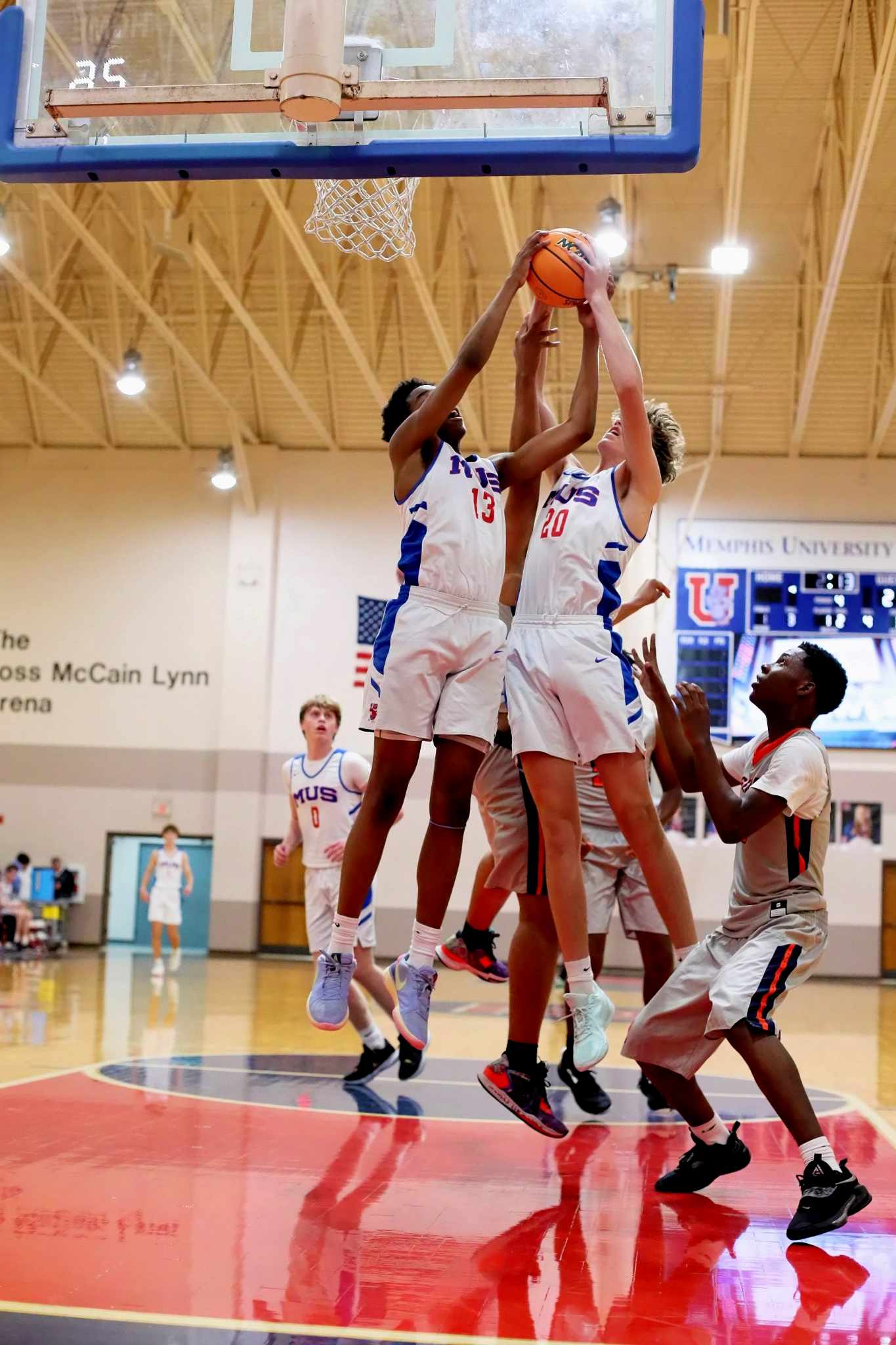 Two basketball players jumping for a rebound.