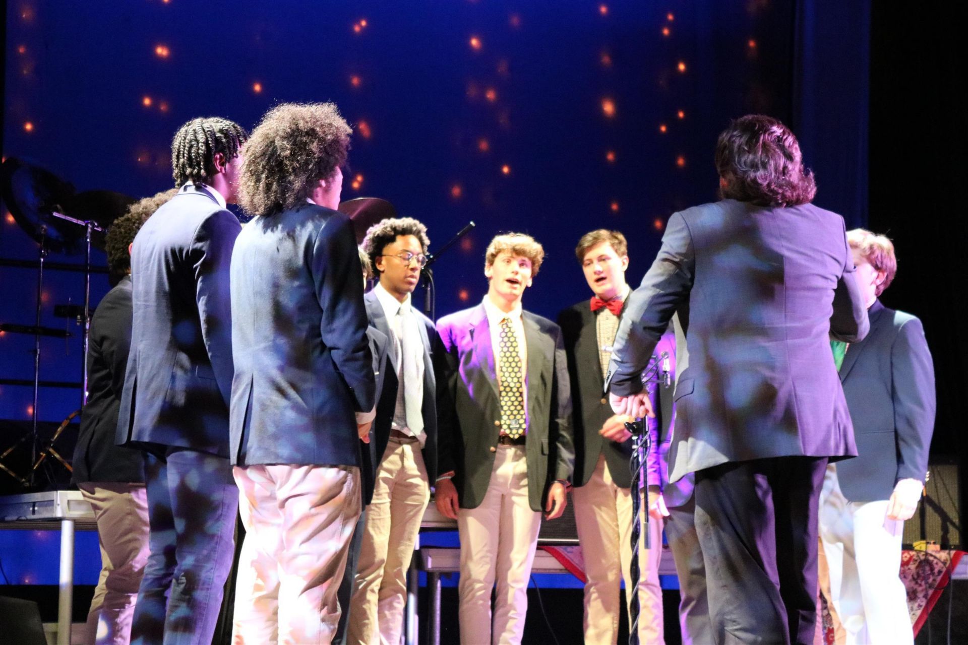 Group of students singing and performing on stage.